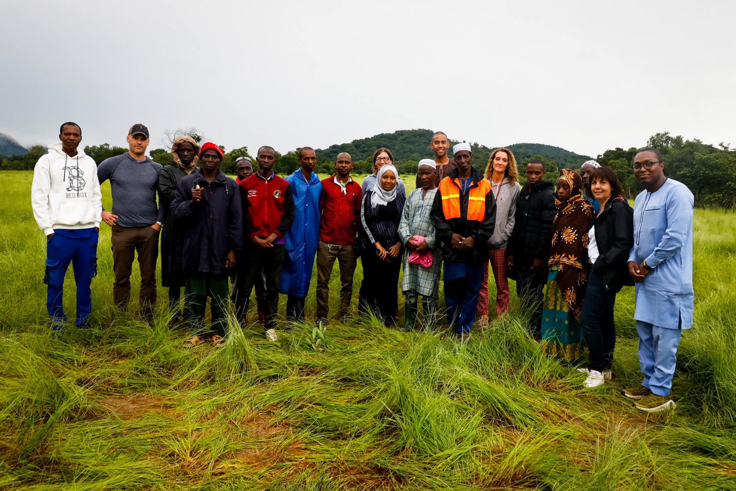 A group of men and women pose for a photo on a fonio farm on a cloudy afternoon in Guinea