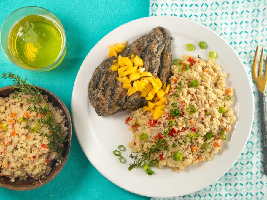 Caribbean Fonio with Jerked Chicken and Mango displayed on a blue table.