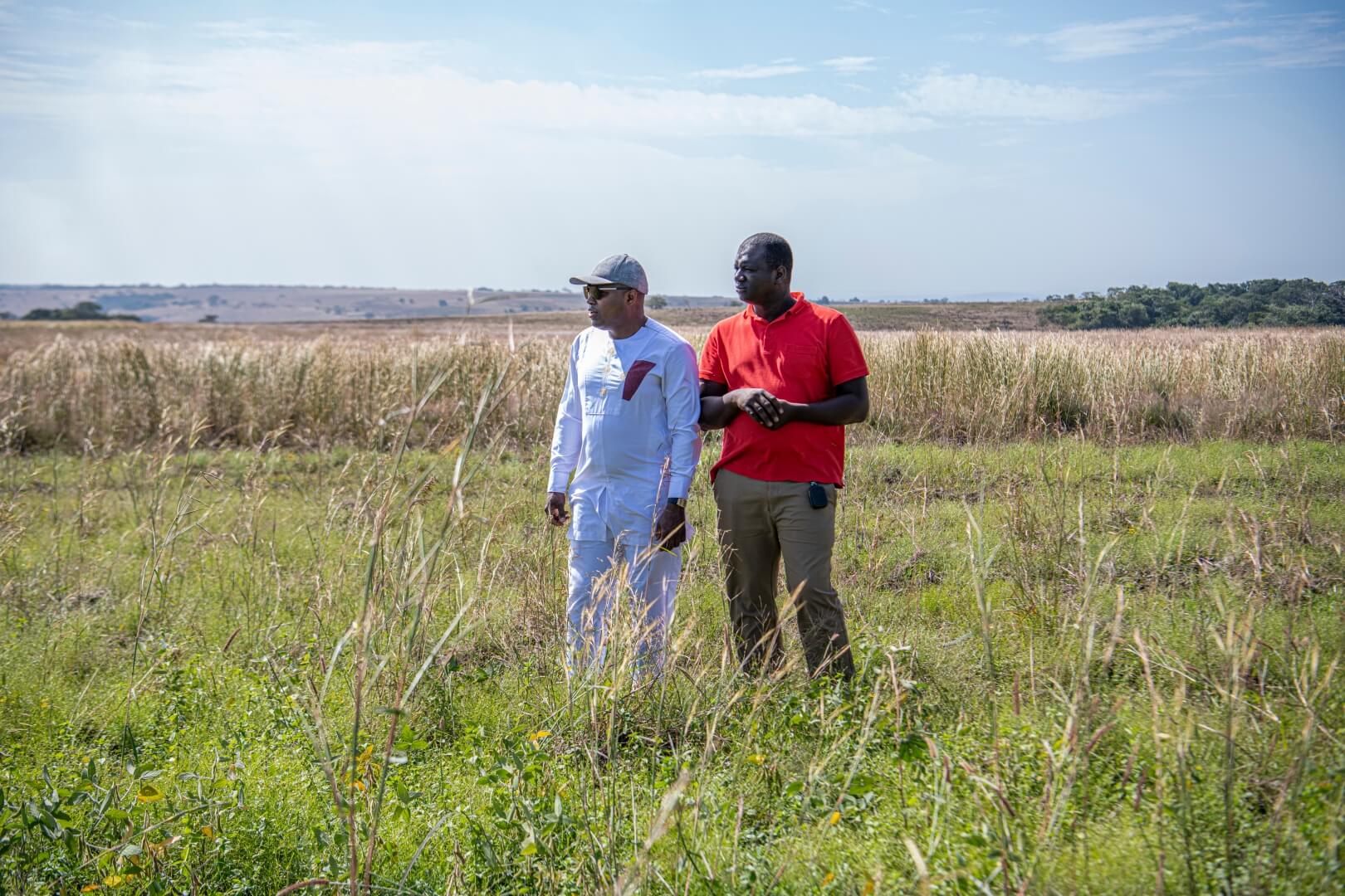 Two men stand in an open farm field